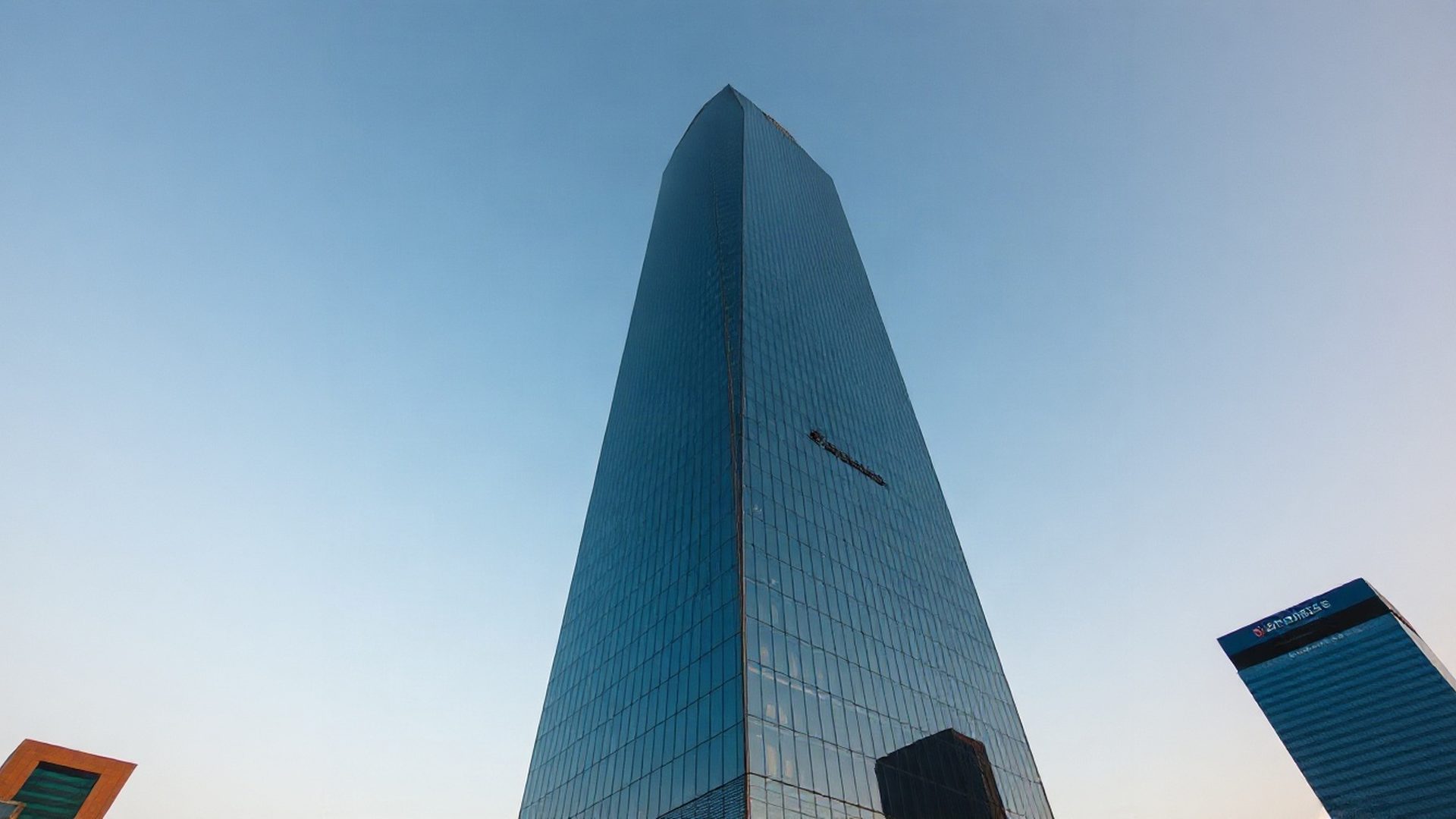 Glass and steel financial tower at dawn under an azure sky